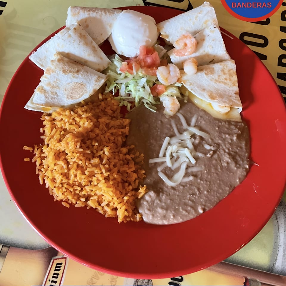 Shrimp quesadillas with rice, refried beans, sour cream, and pico de gallo on a red plate.