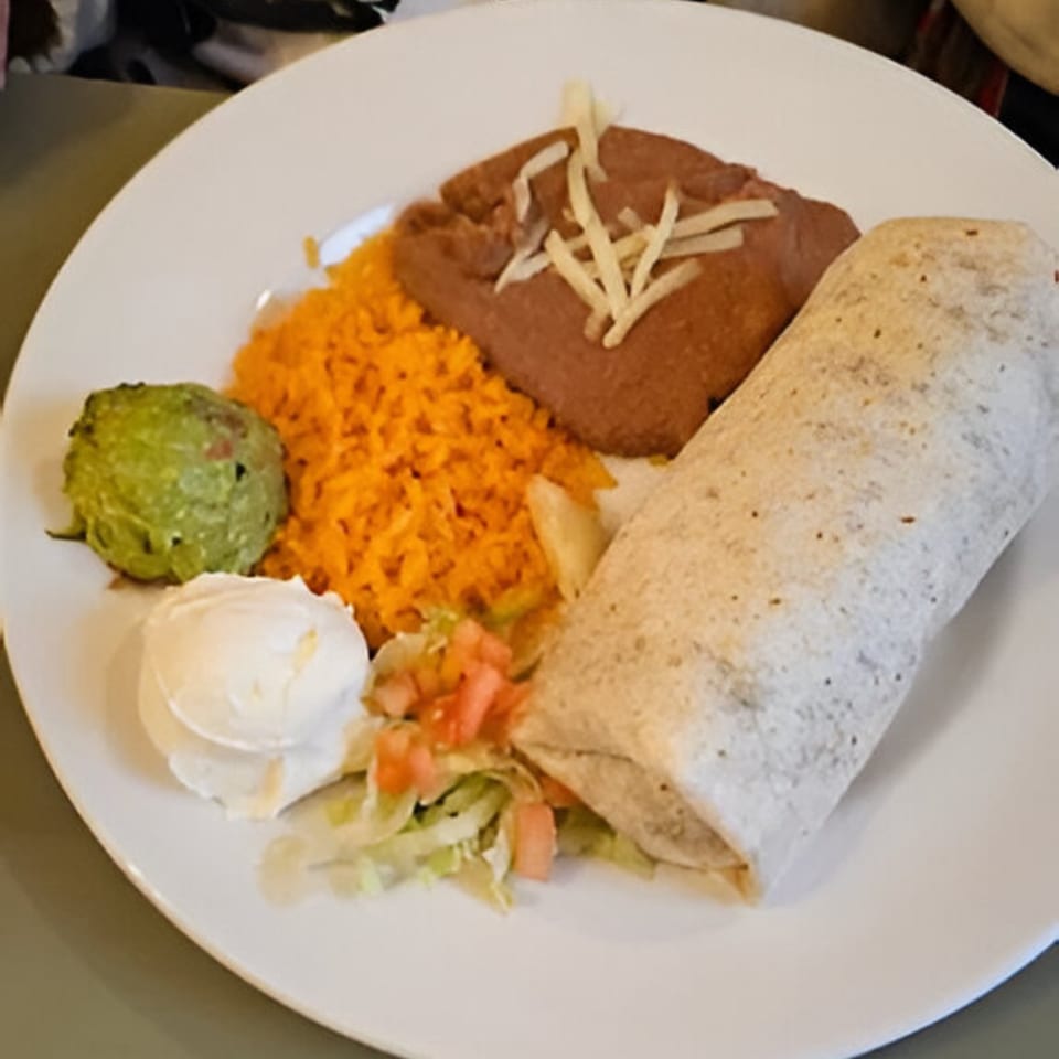 A Dos Banderas burrito plate with rice, refried beans, guacamole, sour cream, and pico de gallo.