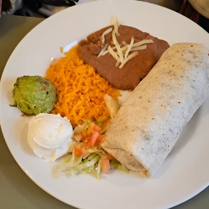 A Dos Banderas burrito plate with rice, refried beans, guacamole, sour cream, and pico de gallo.
