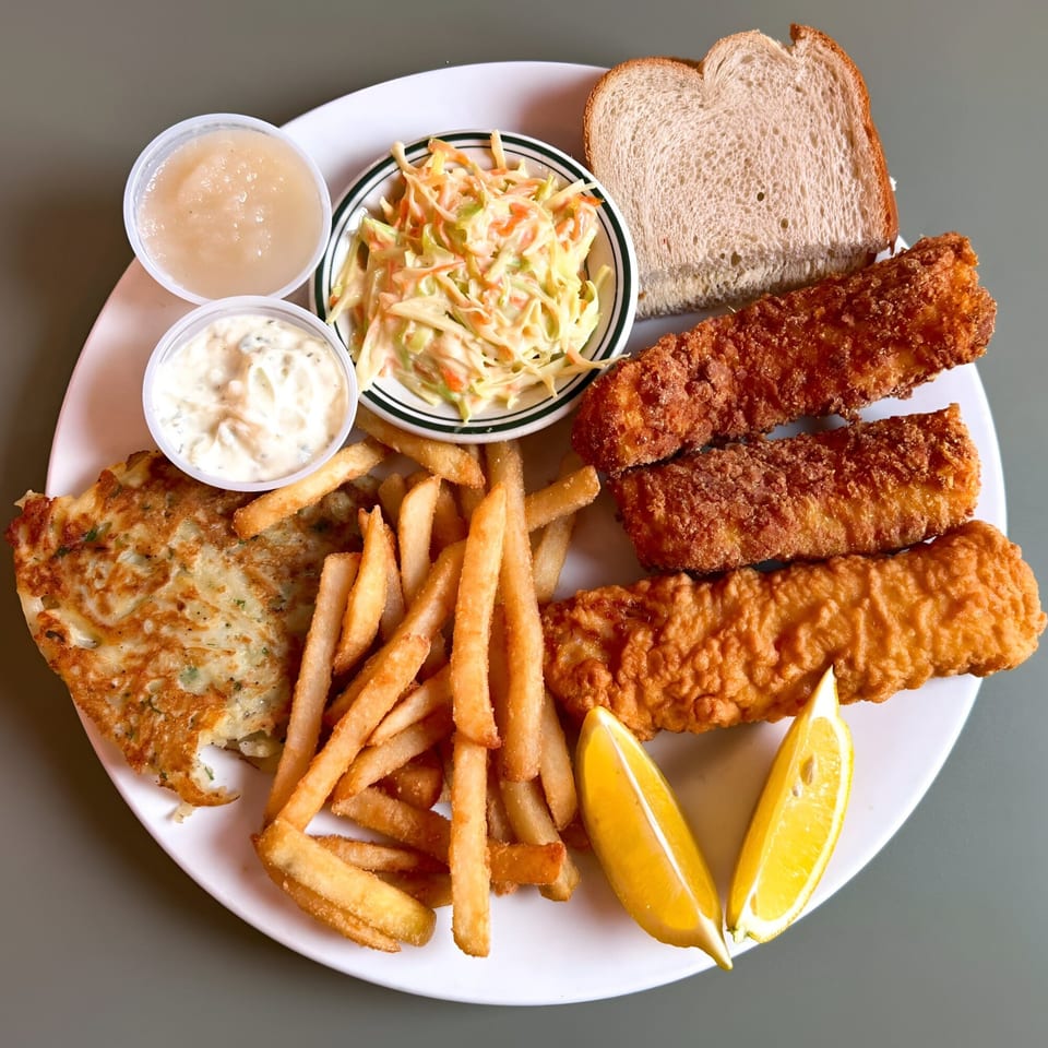A fish fry platter with fried fish, french fries, coleslaw, applesauce, tartar sauce, and bread.