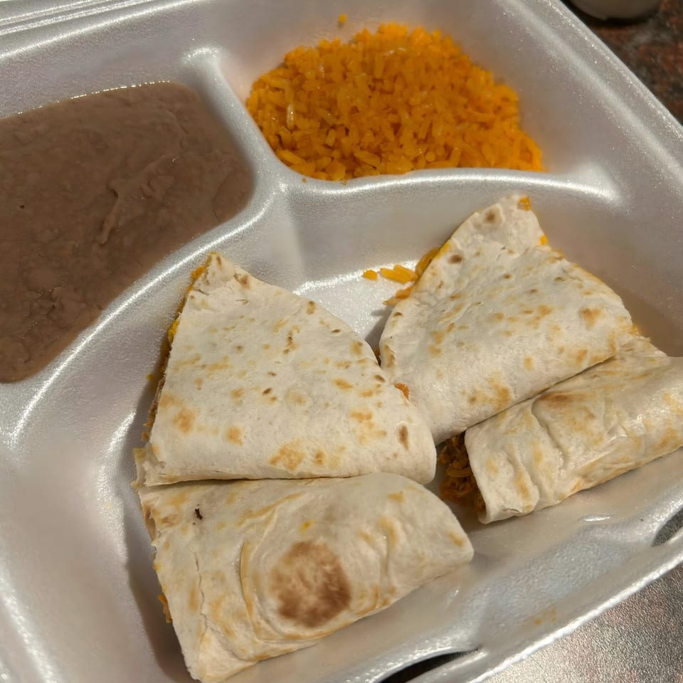 Dos Banderas Mexican restaurant's quesadillas, refried beans, and orange rice in a white takeout container.