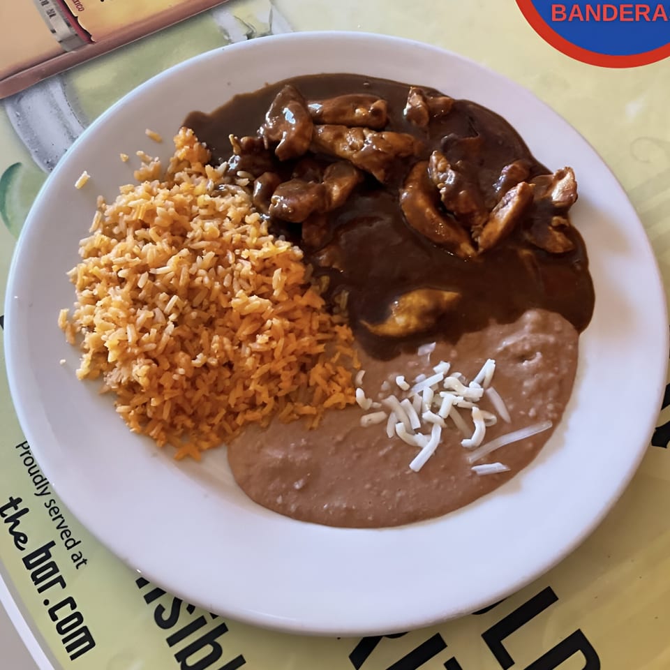 Dos Banderas' chicken mole with rice and refried beans topped with shredded cheese.