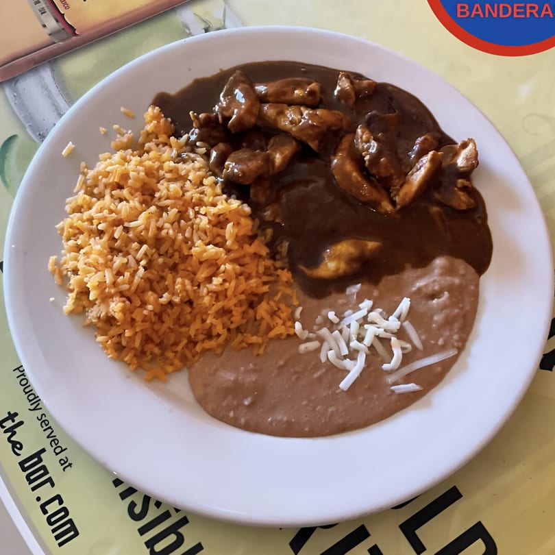 Dos Banderas' chicken mole with rice and refried beans topped with shredded cheese.